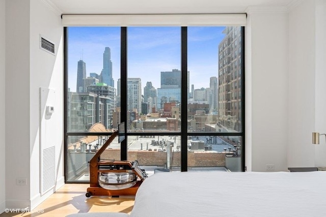 bedroom with visible vents, a city view, floor to ceiling windows, and multiple windows
