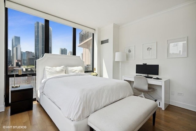 bedroom featuring baseboards, ornamental molding, a city view, and wood finished floors