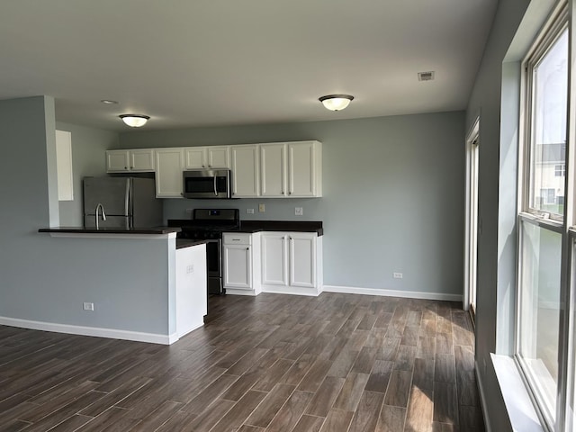 kitchen with dark countertops, appliances with stainless steel finishes, baseboards, and dark wood-type flooring