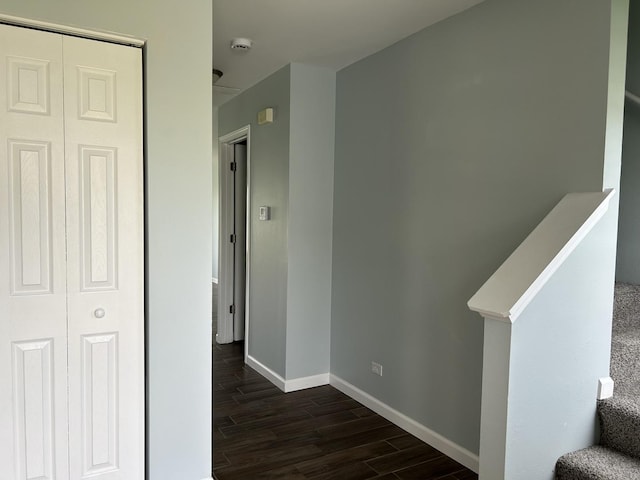 hall with dark wood-style flooring, baseboards, and stairway