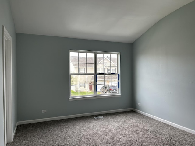 carpeted spare room with baseboards, vaulted ceiling, and visible vents