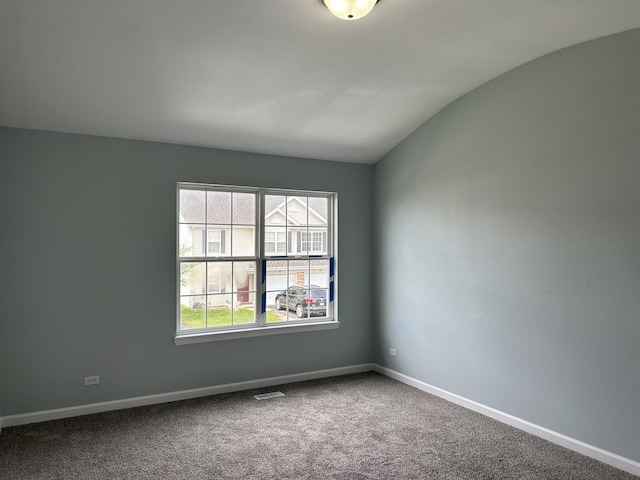 carpeted spare room featuring baseboards, vaulted ceiling, and visible vents
