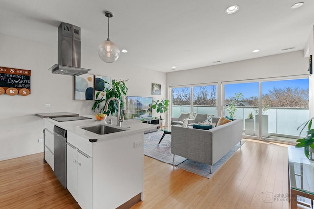 kitchen with recessed lighting, island exhaust hood, stainless steel dishwasher, a sink, and white cabinetry