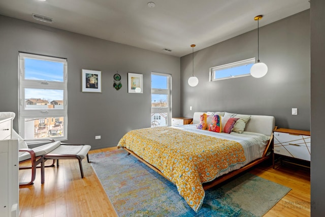 bedroom with baseboards, wood finished floors, and visible vents