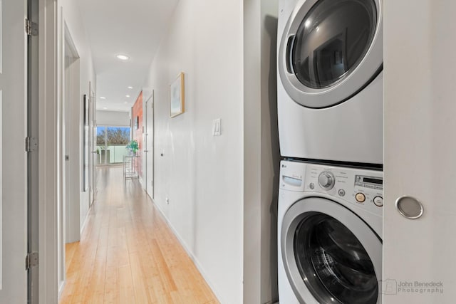 laundry room featuring light wood-style flooring, baseboards, recessed lighting, stacked washer / dryer, and laundry area
