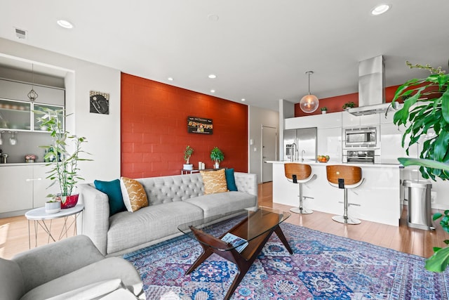 living area featuring recessed lighting, light wood-style flooring, and visible vents