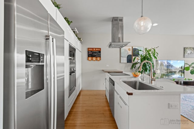 kitchen with light wood-style flooring, appliances with stainless steel finishes, island range hood, and a sink