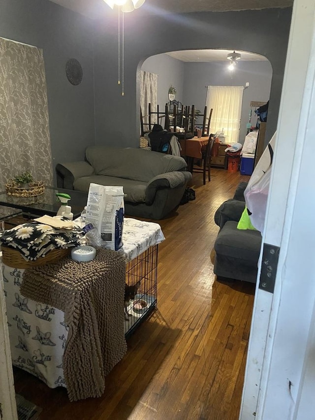 bedroom featuring wood-type flooring, arched walkways, and a ceiling fan