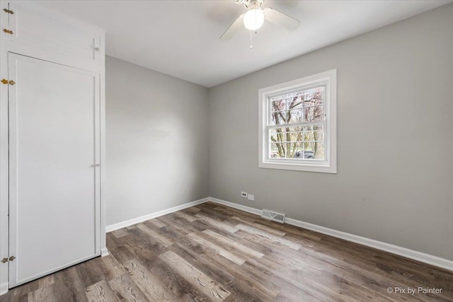 spare room featuring baseboards, a ceiling fan, and wood finished floors