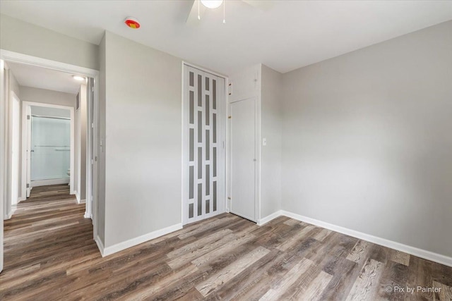 spare room with baseboards, ceiling fan, and wood finished floors