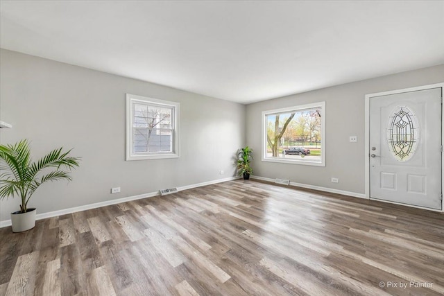 foyer entrance with visible vents, baseboards, and wood finished floors
