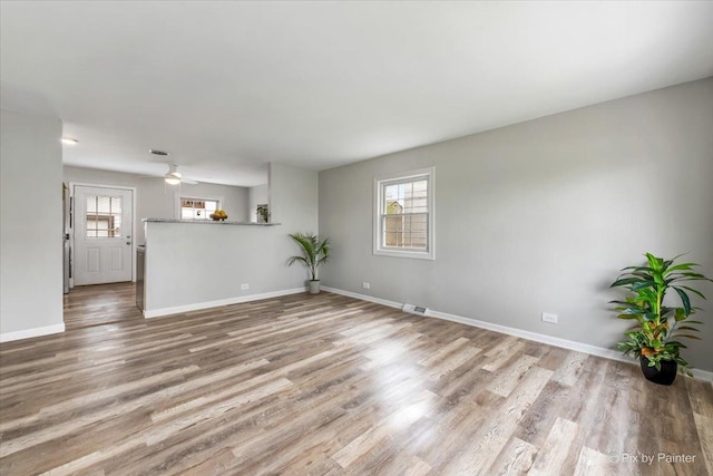 unfurnished living room with baseboards, wood finished floors, and visible vents