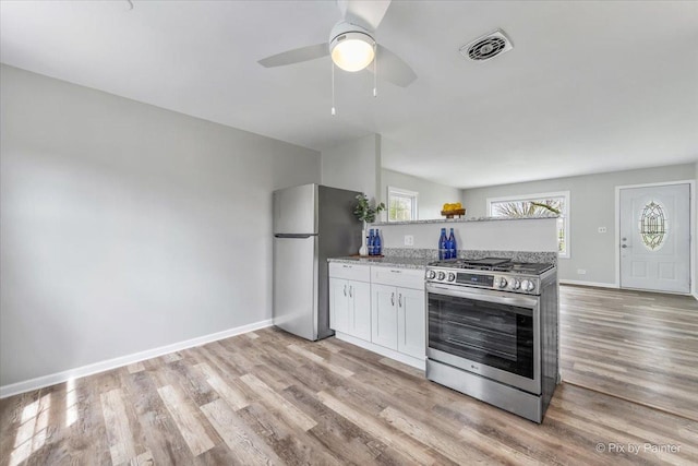 kitchen with visible vents, appliances with stainless steel finishes, light stone countertops, light wood-type flooring, and white cabinets
