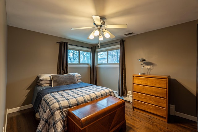 bedroom featuring dark wood-style flooring, a ceiling fan, visible vents, baseboards, and baseboard heating
