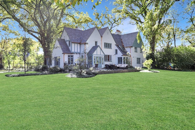 180 De Windt Rd, Winnetka, IL 60093 - back of house with a yard, outdoor lounge area, a chimney, and stucco siding