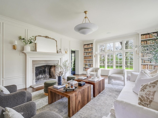 180 De Windt Rd, Winnetka, IL 60093 - living area featuring crown molding, a decorative wall, wood finished floors, a fireplace with raised hearth, and built in shelves