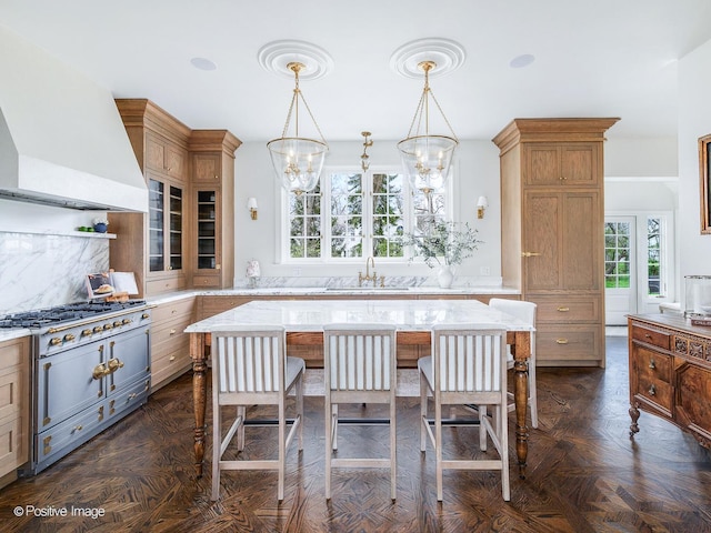 180 De Windt Rd, Winnetka, IL 60093 - kitchen with a kitchen bar, high end stove, a sink, premium range hood, and an inviting chandelier