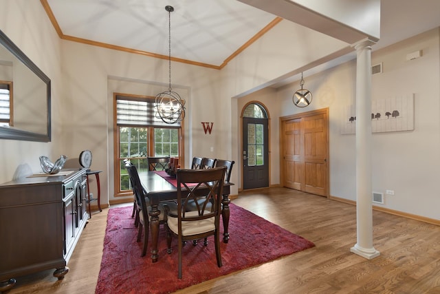 dining room with crown molding, light wood finished floors, visible vents, and ornate columns