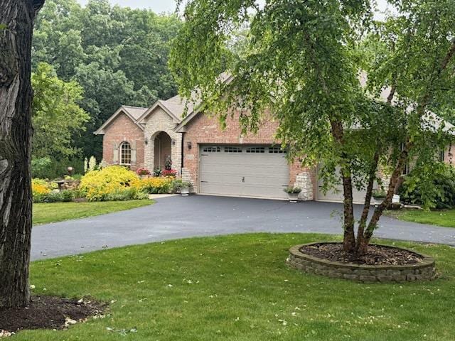 view of front of property with driveway, a front yard, brick siding, and an attached garage