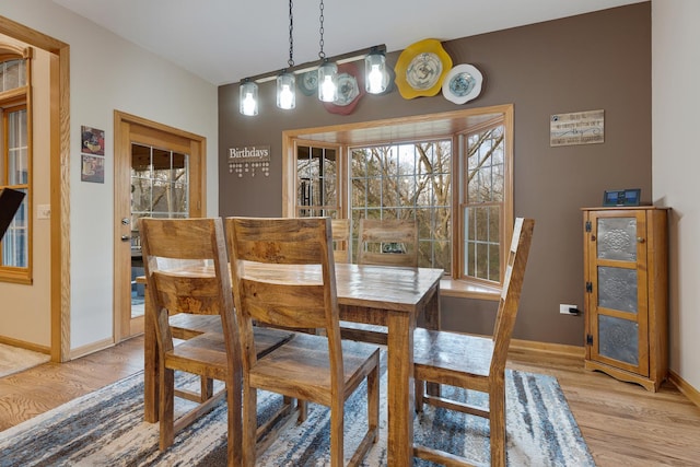 dining space with baseboards, light wood-type flooring, and a healthy amount of sunlight