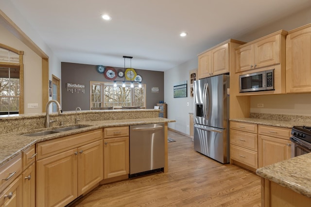 kitchen with light stone counters, light brown cabinetry, appliances with stainless steel finishes, a sink, and light wood-type flooring