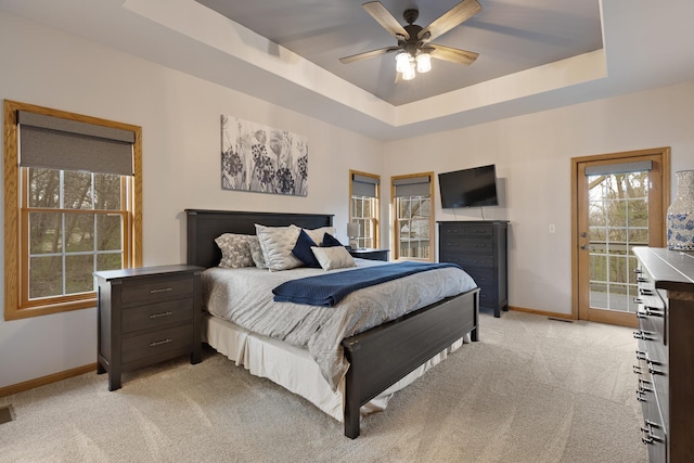 bedroom featuring light carpet, a tray ceiling, access to exterior, and baseboards