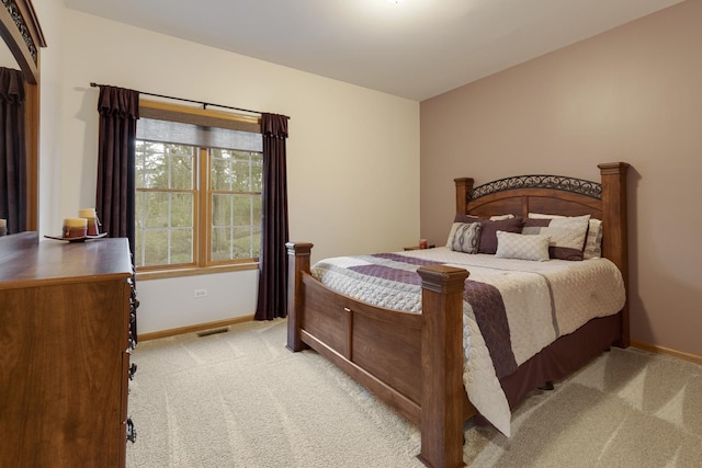 bedroom with baseboards, visible vents, and light colored carpet