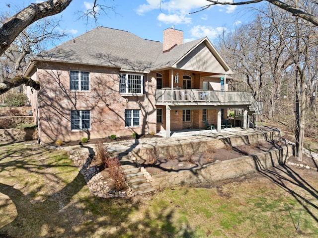 back of property featuring a chimney, brick siding, and a patio area