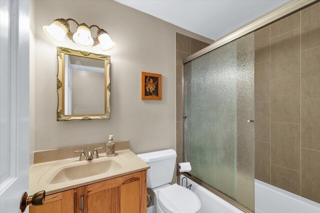 full bathroom featuring vanity, bath / shower combo with glass door, and toilet