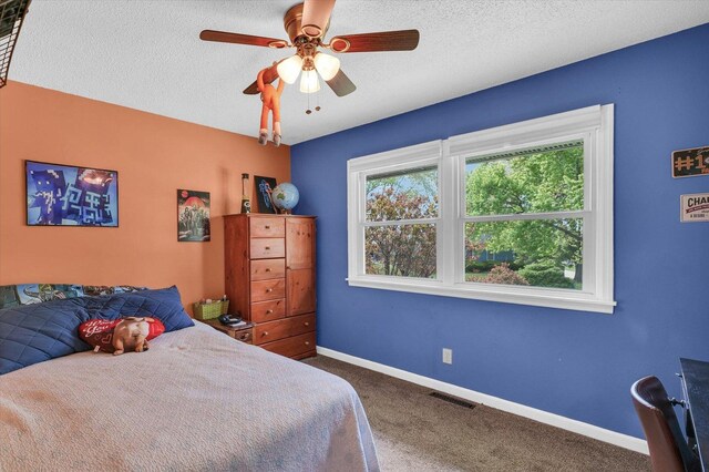 bedroom with a ceiling fan, a textured ceiling, visible vents, carpet floors, and baseboards