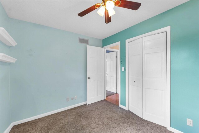 unfurnished bedroom with carpet floors, a ceiling fan, baseboards, visible vents, and a closet