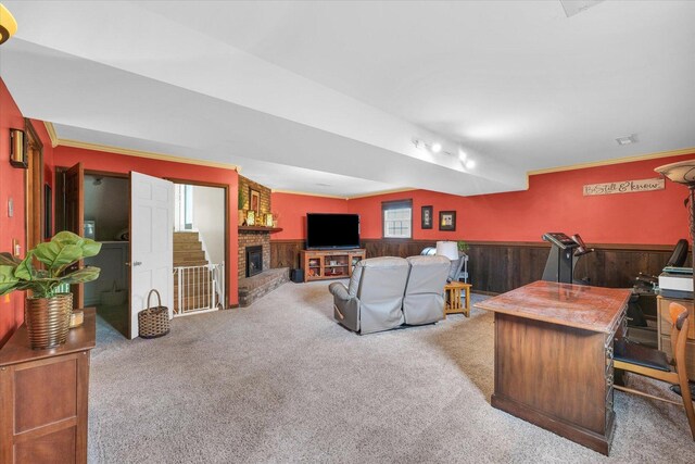 living area featuring crown molding, a brick fireplace, wood walls, a wainscoted wall, and carpet flooring