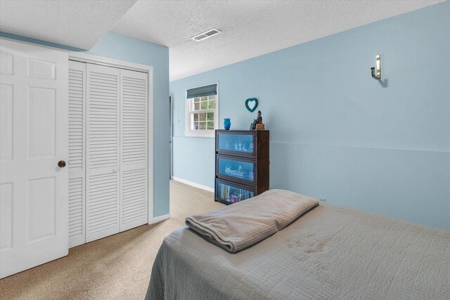 carpeted bedroom featuring a textured ceiling, visible vents, and a closet