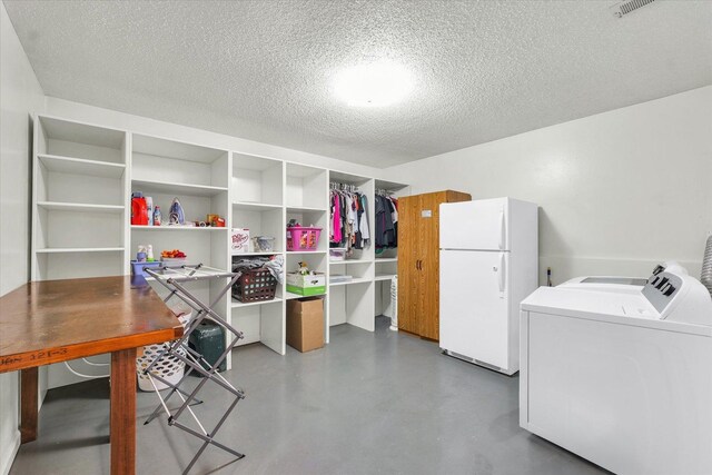 clothes washing area featuring laundry area, a textured ceiling, and washer and clothes dryer