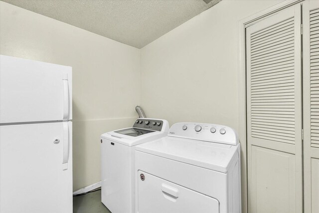 clothes washing area with washer and dryer, a textured ceiling, and laundry area