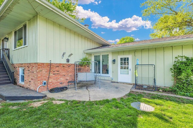 rear view of property featuring a lawn, a patio, board and batten siding, and stairs