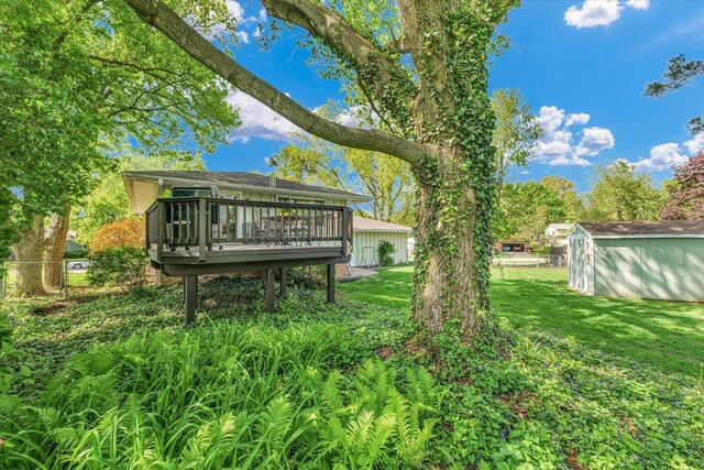 view of yard featuring a storage unit, fence, an outbuilding, and a deck