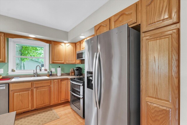 kitchen with visible vents, light countertops, a sink, light wood finished floors, and appliances with stainless steel finishes