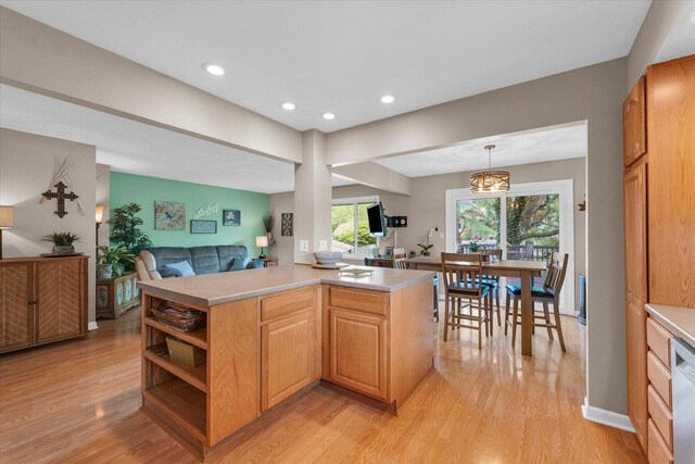 kitchen with light countertops, dishwashing machine, light wood finished floors, and open floor plan