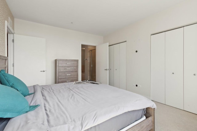 bedroom with multiple closets and light colored carpet