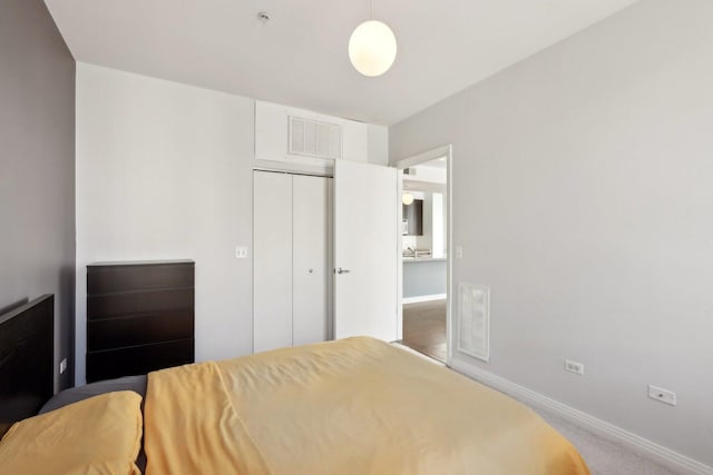 carpeted bedroom featuring baseboards, visible vents, and a closet