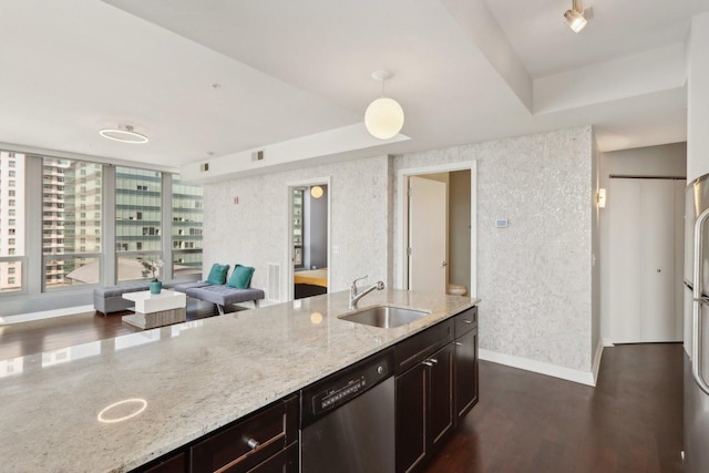 kitchen featuring stainless steel dishwasher, a sink, light stone countertops, baseboards, and dark brown cabinetry
