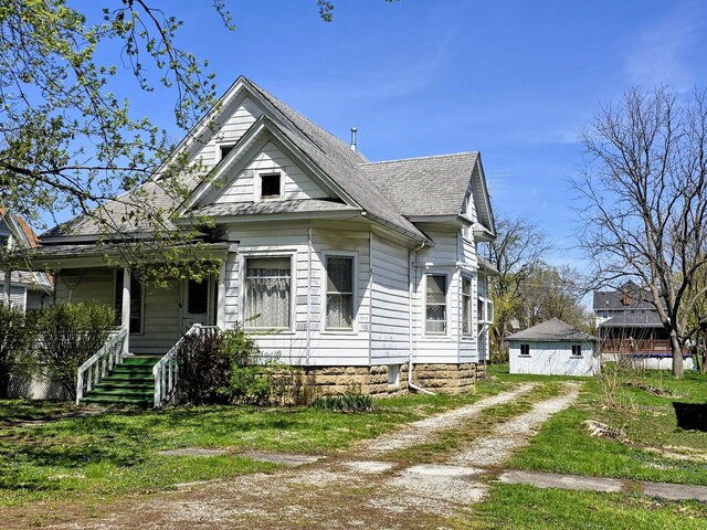 victorian house featuring a shingled roof, driveway, and covered porch