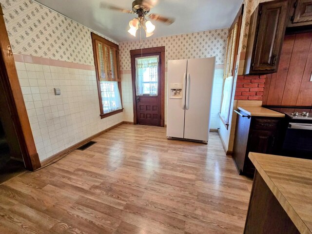kitchen with white fridge with ice dispenser, wallpapered walls, light wood-style flooring, and visible vents