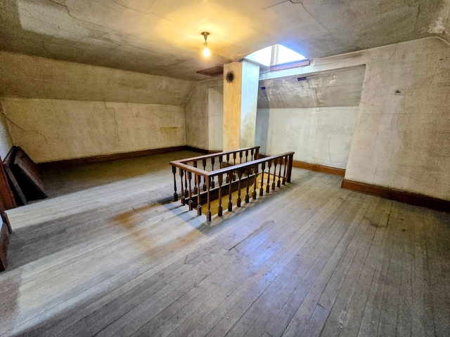 additional living space with hardwood / wood-style floors and lofted ceiling