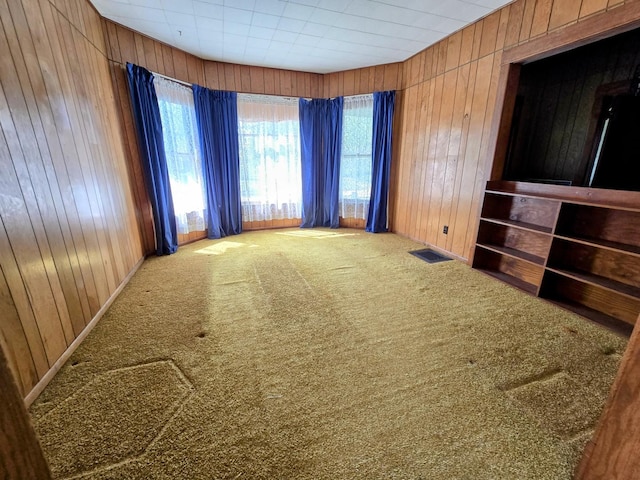 empty room featuring wood walls, visible vents, and plenty of natural light