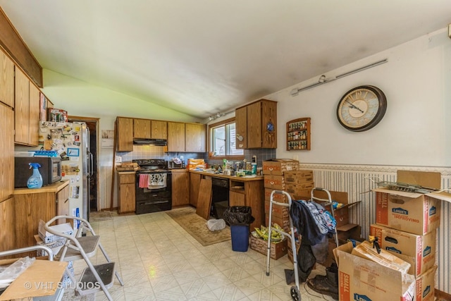 kitchen featuring brown cabinetry, vaulted ceiling, black appliances, light floors, and under cabinet range hood