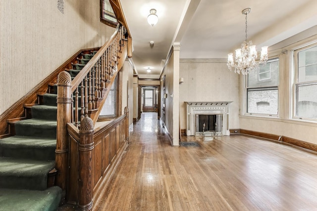 1312 N Astor St, Chicago, IL 60610 - unfurnished living room with wood finished floors, a chandelier, stairway, a fireplace, and wallpapered walls