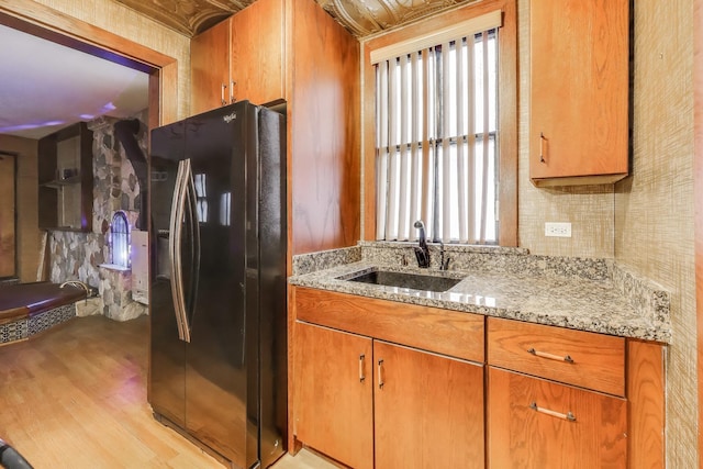 1312 N Astor St, Chicago, IL 60610 - kitchen featuring refrigerator with ice dispenser, a sink, light stone counters, light wood-style floors, and brown cabinets