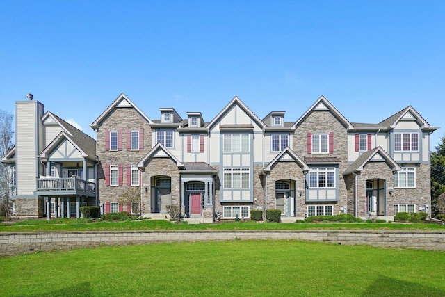 view of front facade featuring stucco siding, stone siding, and a front yard